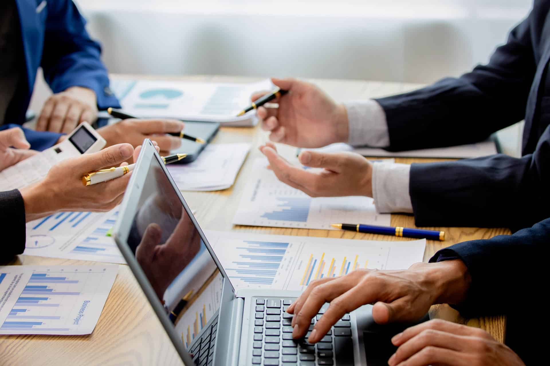 Cuatro personas en una mesa revisando y calculando las cifras de un estudio